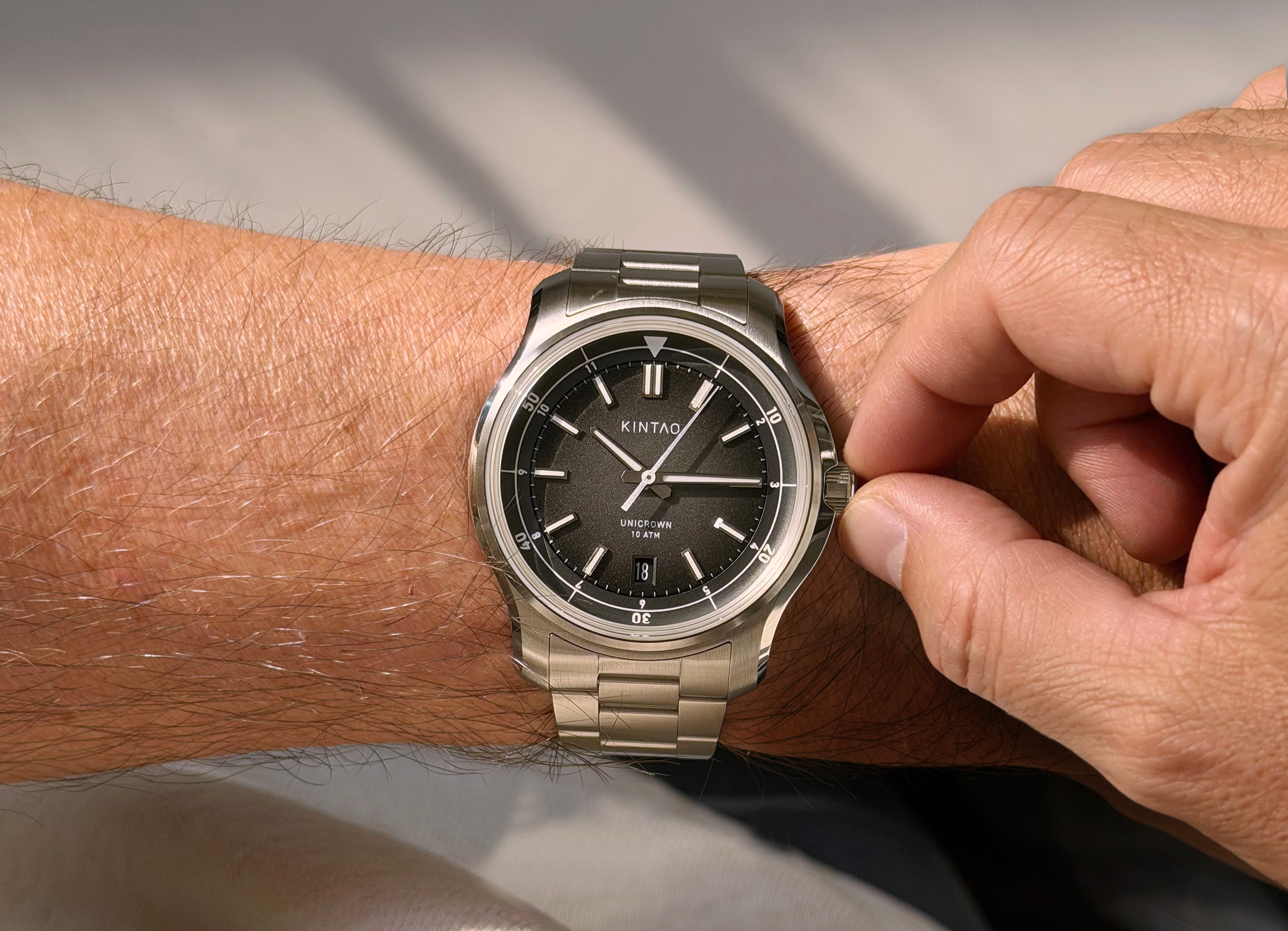 Charcoal UC1 Recurve on the wrist, with fingers turning the Unicrown crown